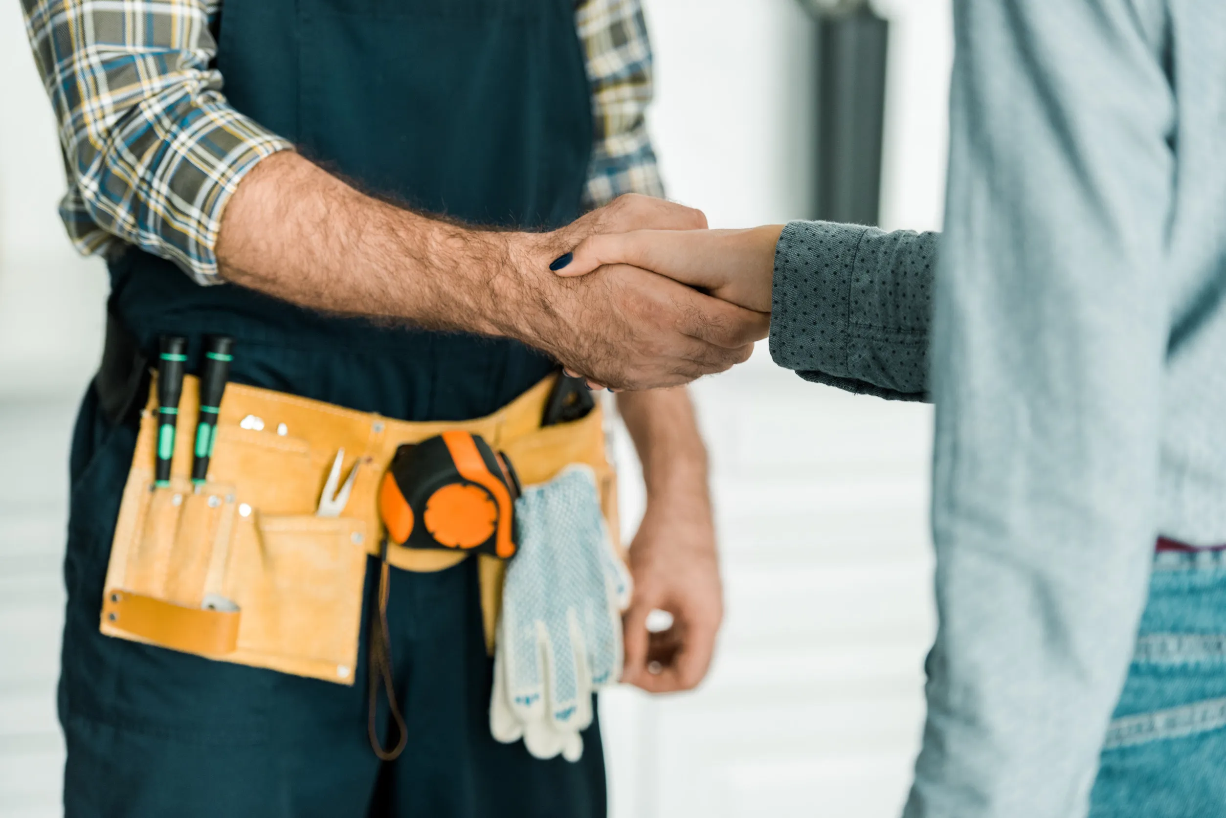 cropped image of plumber and customer shaking hands in kitchen cropped image of plumber and customer shaking hands in kitchen